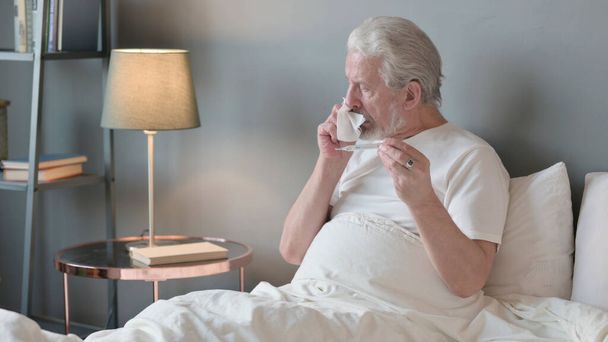 Anciano mayor estornudo Comprobación de temperatura en la cama, termómetro - Foto, Imagen