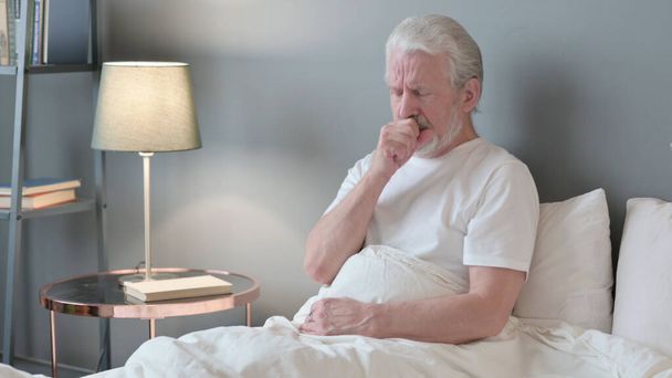 Yaşlı hasta adam yatakta öksürüyor. - Fotoğraf, Görsel