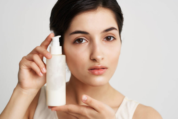 женщина держит рядом с лицом лосьон крупным планом чистой кожи - Фото, изображение