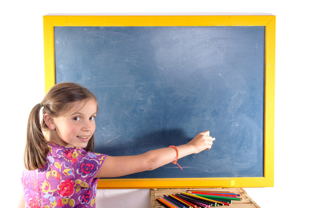 Schoolgirl writing on a blackboard - Фото, изображение