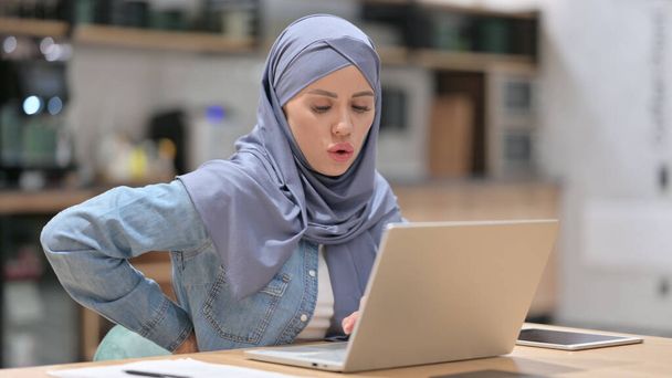 Araberin mit Rückenschmerzen nutzt Laptop bei der Arbeit - Foto, Bild