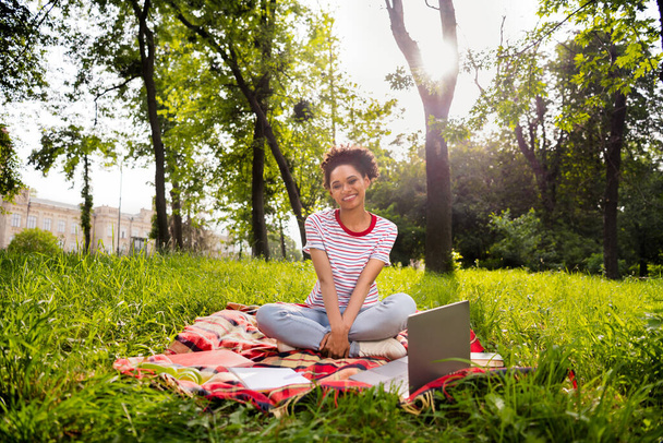 Full length body size happy girl sitting down with laptop preparing for test in city park - Fotó, kép