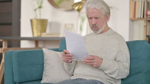 Tense Senior Old Man Reading Documents at Home - 写真・画像