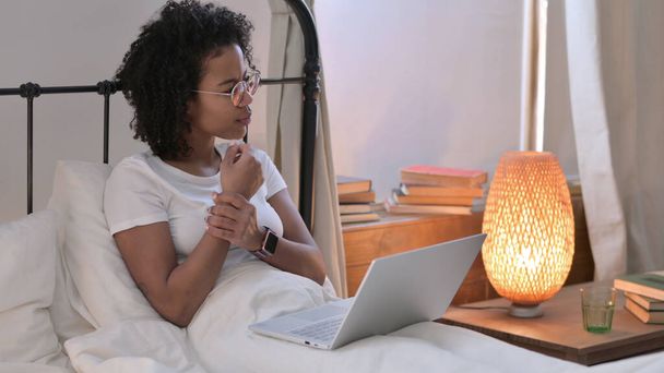 Giovane donna africana con computer portatile con dolore al polso a letto - Foto, immagini