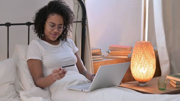 Succès des achats en ligne sur ordinateur portable par la jeune femme africaine à la maison - Photo, image