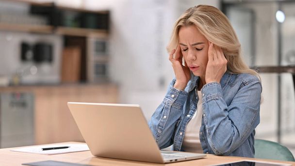 Mujer joven casual con dolor de cabeza usando el ordenador portátil en el trabajo - Foto, imagen