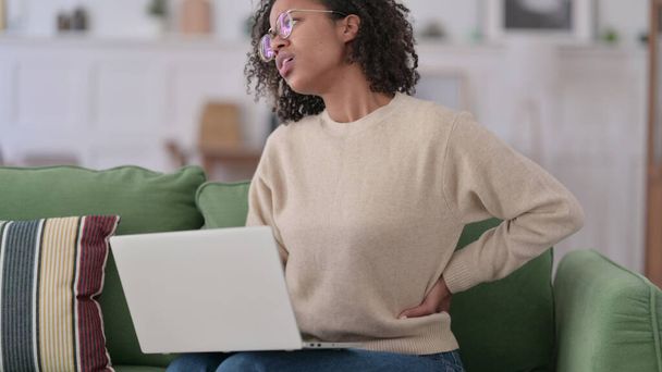 Jovem mulher africana com laptop tendo dor nas costas em casa - Foto, Imagem