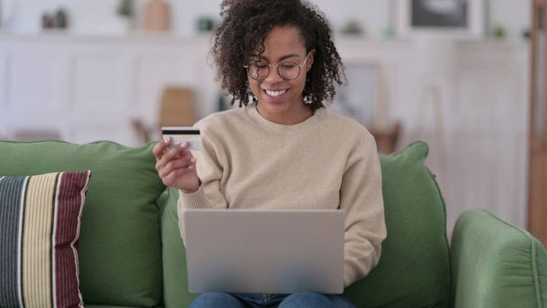 Compras en línea Éxito en el ordenador portátil por la mujer africana joven en el hogar - Foto, imagen