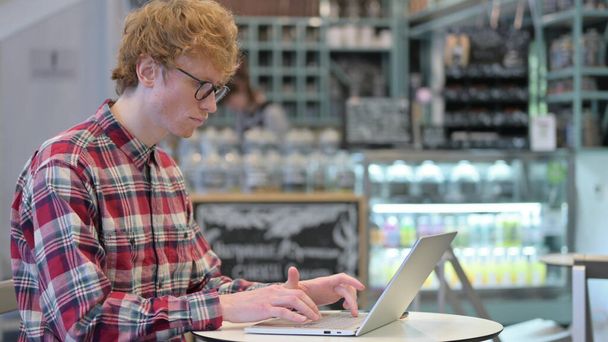 Redhead νεαρός άνδρας στο καφέ χρησιμοποιώντας Laptop - Φωτογραφία, εικόνα