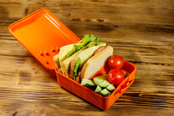 Tahta bir masada sandviç ve taze sebzelerle beslenme çantası. - Fotoğraf, Görsel
