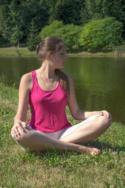 A jovem praticando ioga junto ao lago
 - Foto, Imagem