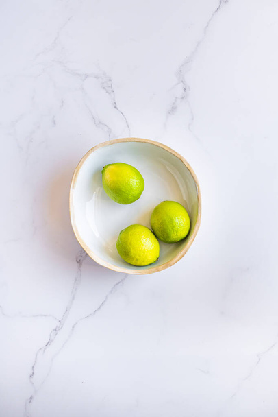 3 limes in a fruit bowl on marble surface - Foto, immagini