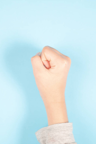 A vertical shot of a child's fist on a light blue background - Фото, зображення