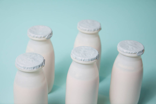 Bottles with probiotics and prebiotics dairy drink on light blue background. Bio yogurt with useful microorganisms. Production with biologically active additives. Fermentation and diet healthy food. - Photo, Image