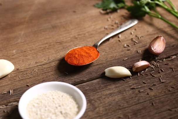 Cooking ingredients on wooden table: sesame, paprika, garlic and aniseed. - Foto, afbeelding