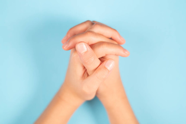 A felső nézet a gyermek összefonódó kezét egy világoskék háttér - Fotó, kép