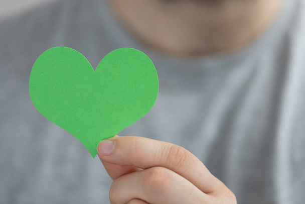 A person presenting the virtual projection of a green paper heart - Foto, Imagem