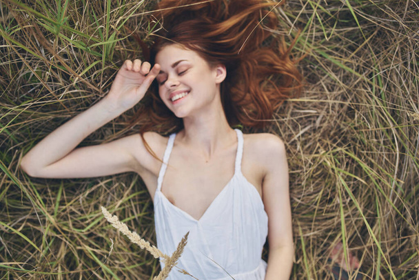 白いドレスの陽気な女性は草の生活レジャーの自由に横たわっています - 写真・画像