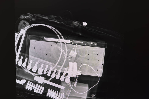 Xray image of a wrenches set,  an electrical device with dry cell batteries,  and some cables in the bag. - Photo, Image