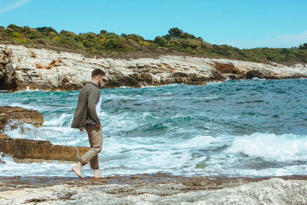 man walking by rocky beach in windy day summer vacation. enjoy sea view. summer time - Photo, Image