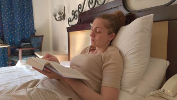 Kobieta w łóżku czytając książkę - Materiał filmowy, wideo
