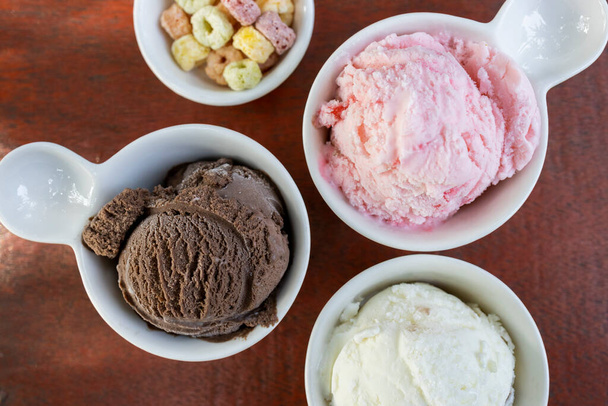 Невелика порція трьох різних лопатей морозива в білих керамічних чашках
. - Фото, зображення
