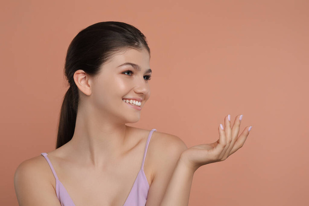 Portrait of pretty girl on pale coral background, space for text. Beautiful face with perfect smooth skin - Foto, imagen