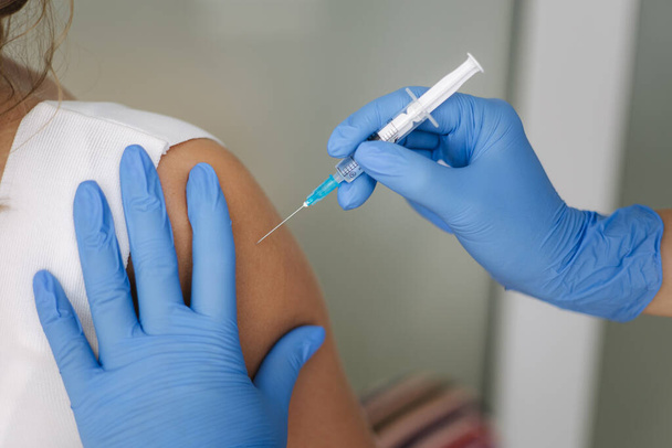 Médica em luvas de proteção segurando seringa fazendo vacinação vívida 19. Mulheres a receber injecção no ombro. Conceito de ensaios clínicos da vacina, vírus da corona - Foto, Imagem