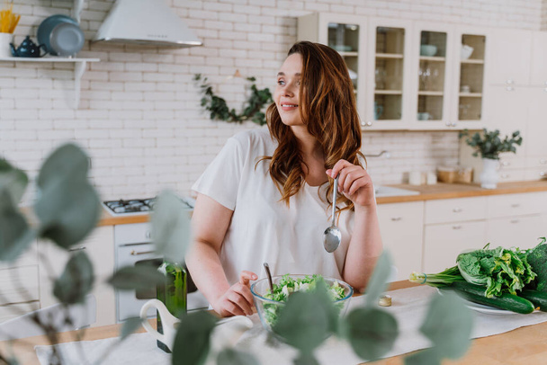 Lifestyle momenten van een jonge vrouw thuis. Vrouw bereidt een salade in de keuken - Foto, afbeelding