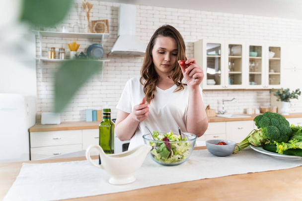 Стиль жизни молодой женщины дома. Женщина готовит салат на кухне - Фото, изображение