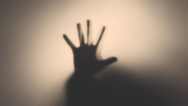 Silhouette of a man's hand behind a translucent glass. The concept of the other world, victims of violence, paronormal, ghosts. - Фото, изображение
