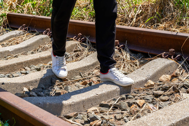 A man walking on old rusty railway tracks outdoors - Zdjęcie, obraz