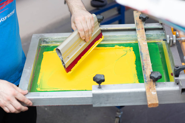 Serigrafia proces drukowania sitodruku w fabryce odzieży. Farby barwnikowe ramowe, squeegee i plastisol - Zdjęcie, obraz