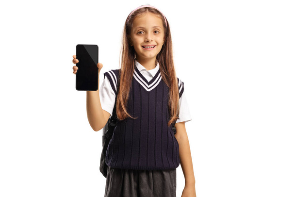 Cute schoolgirl showing a smartphone isolated on white background - Фото, изображение