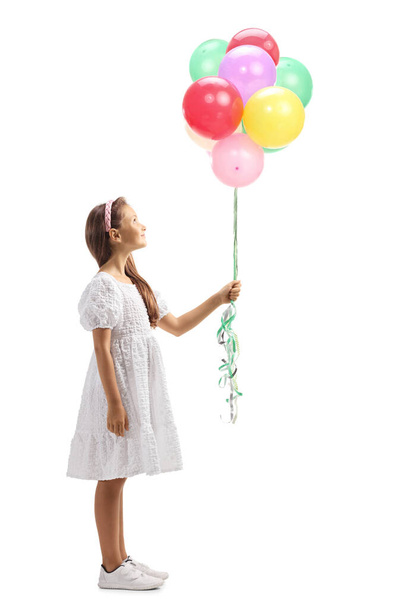 Full length profile shot of a girl in a white dress balloons and looking up isolated on white background - Φωτογραφία, εικόνα