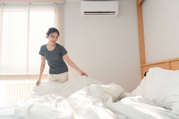 Ložnice koncept žena dospělý dělá rutinu tím, že uchopí okraj přikrývky pro ustlání postele po vstávání v ranním čase. - Fotografie, Obrázek