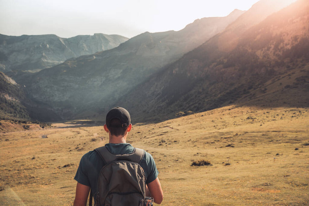 Shot from the back of a young man trekking on the top of a green mountain enjoying the amazing landscape views during sunset. Paradise grass mountain. Lifestyle relax and freedom.  - Foto, imagen