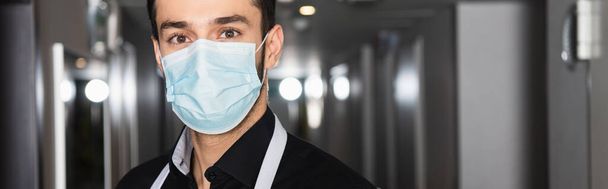 экономка в медицинской маске, смотрящая в камеру, баннер - Фото, изображение