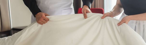 обрезанный вид горничных, меняющих постельное белье в гостиничном номере, баннер - Фото, изображение