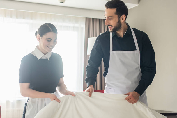 Gülümseyen temizlikçiler otel odasında yatak değiştiriyor.  - Fotoğraf, Görsel