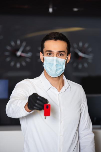 ρεσεψιονίστ σε ιατρική μάσκα κρατώντας θολή κλειδί δωματίου  - Φωτογραφία, εικόνα