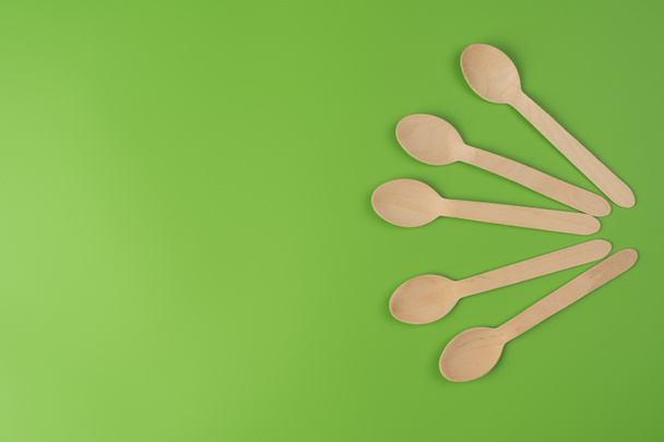 Spoons are arranged in a row. Eco-friendly tableware from green color background - Foto, Imagem