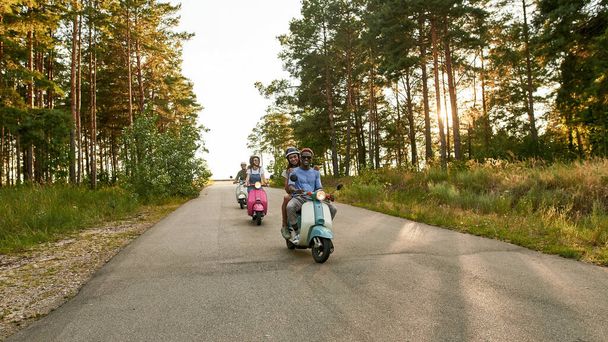 Smiling young multiracial people riding retro scooters - Foto, afbeelding