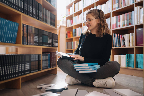 Nastolatka wybierająca książkę na półce bibliotecznej - Zdjęcie, obraz
