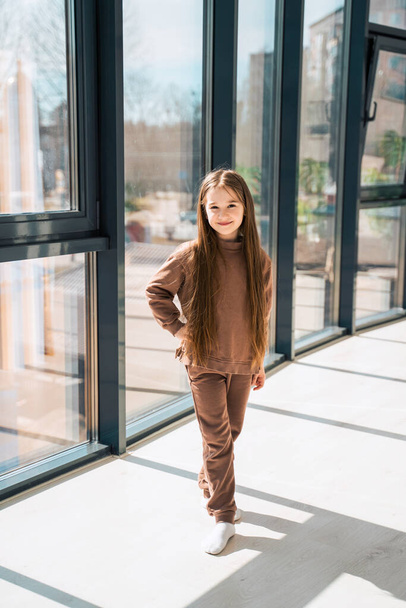 Porträt eines schönen kleinen Mädchens in brauner Kleidung - Foto, Bild