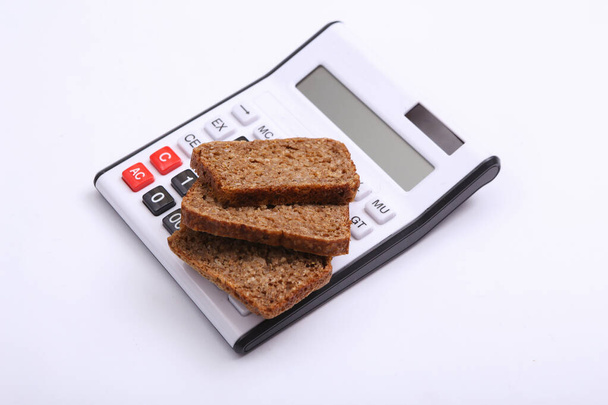 Calcolatrice con pane affettato integrale di segale su fondo bianco. Dieta, concetto di conteggio delle calorie - Foto, immagini