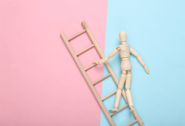 Drewniana marionetka wspina się po schodach na niebiesko-różowym pastelowym tle. Koncepcja rozwoju kariery - Zdjęcie, obraz