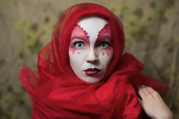 Mysterious mystical woman with a face painted white-red. - 写真・画像