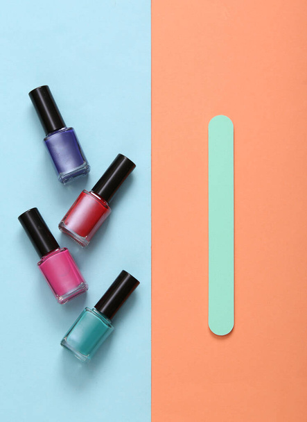 Nail polish bottles and nail file on blue pink pastel background - Zdjęcie, obraz