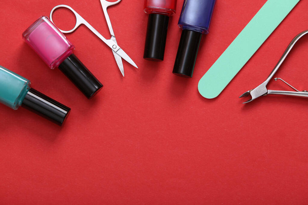 Manicure accessories. Nail polish bottles, scissors and nail file on red background. Top view. Flat lay. Copy space - Photo, Image